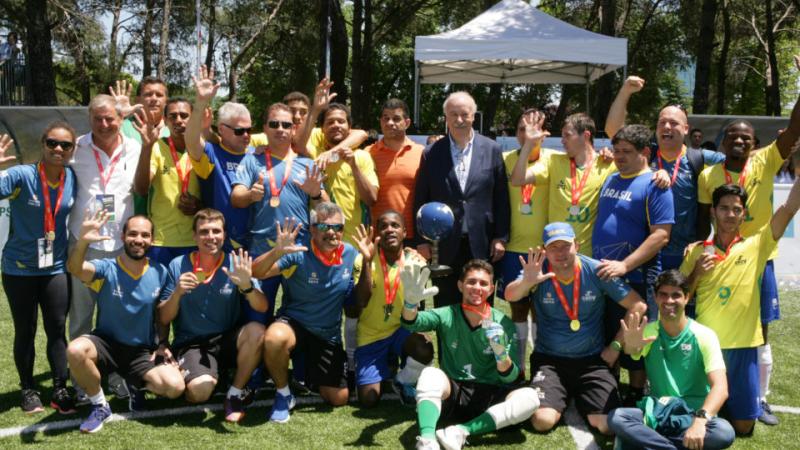 a group of male blind footballers wearing Brazil shirts and holding their hands up in celebration